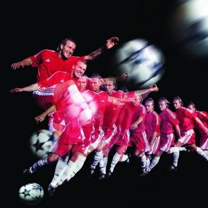 David Beckham by Howard Schatz, multiple exposure of the football star runnng at the ball and shooting, in red tricot