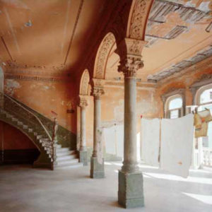'La Guarida', Restaurant Entrance 418 Concordia Vedado, Havana. 1997 by Robert Polidori, old and broken down baroque hall with columns and staircase, orange walls and laundry