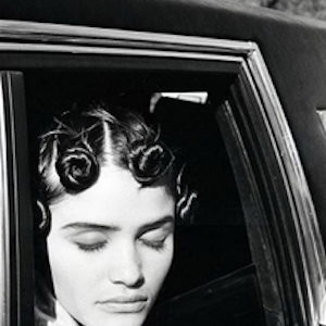 Helena Christensen. 1990 by Arthur Elgort, the model in tied up curlsenjoying the sun out of a carwindow with closed eyes