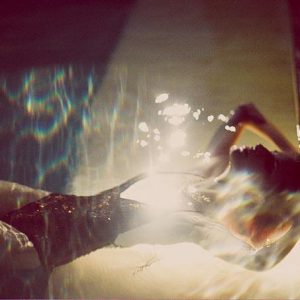 linda 6 by Guy Aroch, model in black Sequin bathingsuit floating in a pool