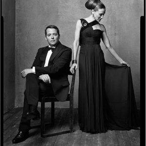 Mathew Broderick and Sarah Jessica Parker by Mark Seliger, matthew in a black suit sitting on a chair, right next to hom sarah jessica Parker in a black own with broach