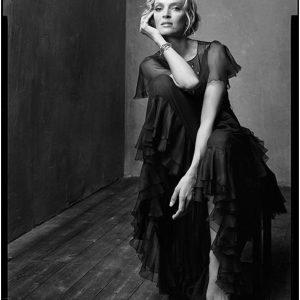 Uma Thurman by Mark Seliger, the actress in a black ruffle dress sitting on a chair