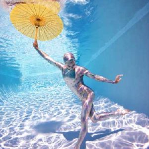 Underwater Study #2778 by Howard Schatz, model in pastel leotard and cap, holding a yellow umbrella underwater in a pool