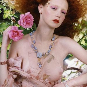 Red Hair 2 by Iris Brosch, portrait of a model with curly red hair wearing transparent flower fabric and holding two pink flowers