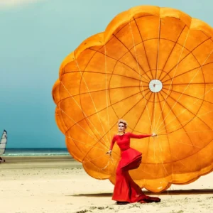 Nadja III by Kristian Schuller, Nadja Auermann in red dress with orange parachute on the beach