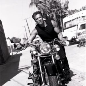 ArnoldSchwarzenegger by Sante D'Orazio, the bodybuilder in a black tanktop pushing a harleay davidson motorbike
