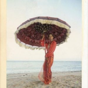 Leticia H. for L'Officiel Bali by Bruno Bisang, model in red dress standing on a beach and holding a purple parasol