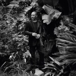 Eddie Murphy, Los Angeles, CA, 2019 by Mark Seliger, black and white portrait of the actor in a velvet suit between plants