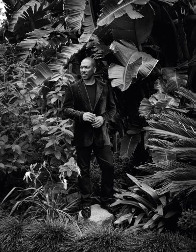 Eddie Murphy, Los Angeles, CA, 2019 by Mark Seliger, black and white portrait of the actor in a velvet suit between plants