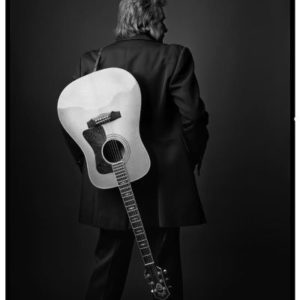 Johnny Cash, Las Vegas, 1992, the singer in a black suit with a guitar over his shoulder, turning his back to the camera