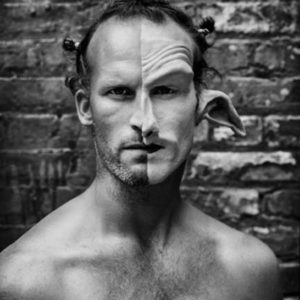 Matthew Barney by Mark Seliger, the artist in front of a brick wall, paritially in makeup for the movie cremaster