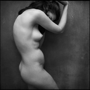 Nude by Mark Seliger, nude model in profile, hiding her face behind her arm