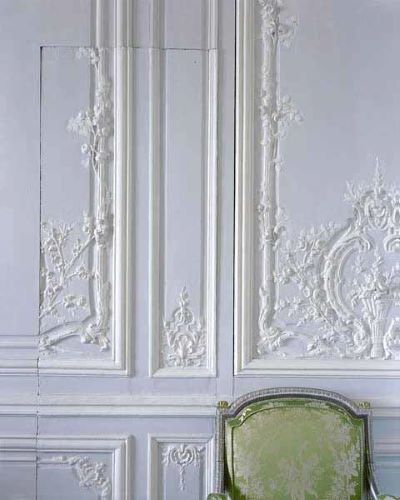 White wall with baroque stucco decor, 'invisible' servants door and green and silver embroidered chair