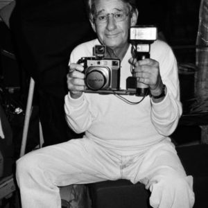 Helmut Newton, Paris by Roxanne Lowit, the photographer dressed in white holding a mamiya Camera