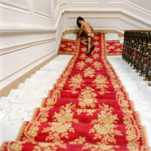 Margeritha on stairs II by Guido Argentini, model in black stockings and heels lying at the foot of a staircase