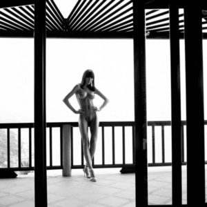 The truth is standing in front of you by Guido Argentini, nude model leaning on a black terrace railing