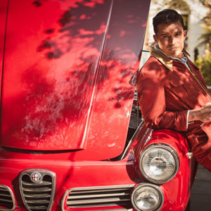 Orlando Bloom II by Guy Aroch, the actor in a red onepiece holding a wrench and leaning on a red oldtimer car with open engine hood