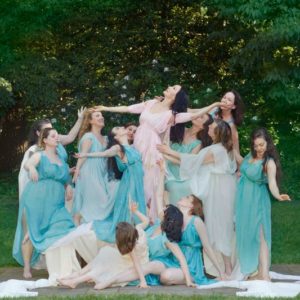 Duncan by Iris Brosch, a group of women in white blue and pink greek inspired gowns posing in a garden looking up