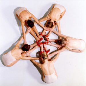 Vogue Italia by Iris Brosch, five models in nude leotards and red heels sitting in a circle bending over, reating the shape of a star