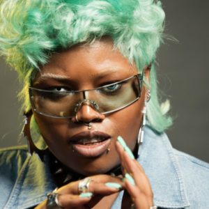 Raisa Flowers by Marc Baptiste, portrait of the influencer and Makerupartist in green mullet and nails, wearing glasses and colored contact lenses