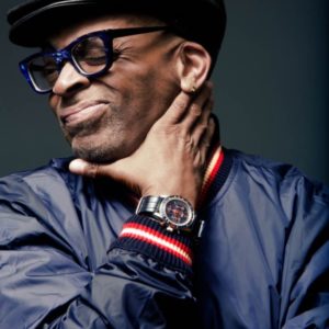 Spike Lee ROLEX by Marc Baptiste, portrait of the director and actor in a blue jacket and glasses with a black leather heat showing off a rolex watch