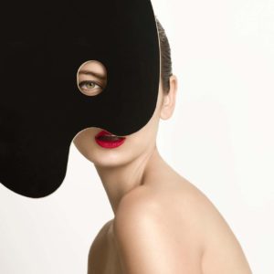 Hanna One by Sylvie Blum, portrait of unde model in red lip, a black shape covering hr face so only one eye and her mouth are visible
