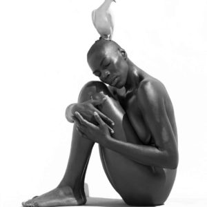 The bird on my mind by Sylvie Blum, model sitting with bent knees, a white pigeon on her head