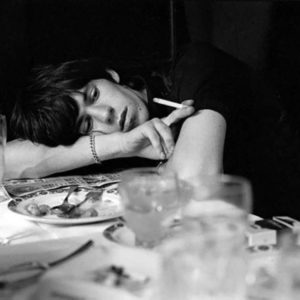 Keith Richards by Terry O'Neill, the musician leaning on a set table, smoking