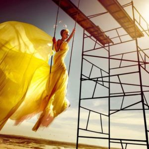 Beach by Kristian Schuller, Model in yellow dress and headpiece on rings at the beach