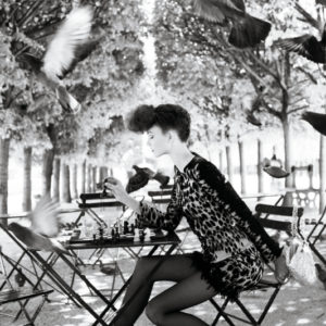 Karlie Kloss, Knight takes pawn by Arthur Elgort, the model in a short spotted dress sitting in a park playing chess surrounded by doves