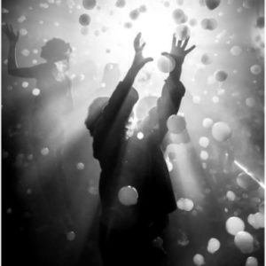 boy balloons by Gérard Uféras, figures between plastic balls in front of a bright light